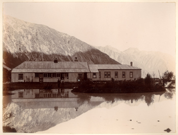 Alpi meridionali della Nuova Zelanda: Borsalino e Zurbrigghen davanti ad  un edificio in lamiera sulle sponde di uno specchio d'acqua