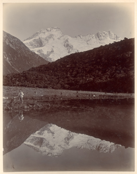 Alpi meridionali della Nuova Zelanda: Mattia Zurbrigghen sulle sponde di un lago con montagne sullo sfondo (M. Cook?)