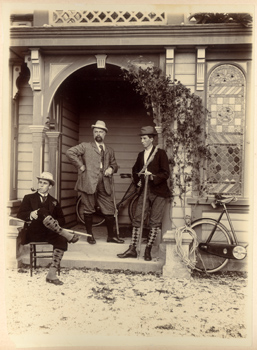 Nuova Zelanda:  tre uomini in tenuta da escursionisti (tra cui J.J. Kinsey?) ritratti sulla veranda di un cottage in legno